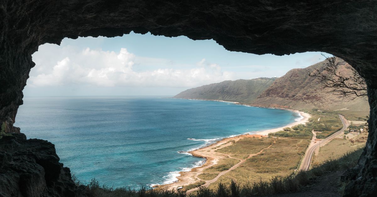 Coastal landscape viewed from inside a cave, ocean waves and horizon beyond