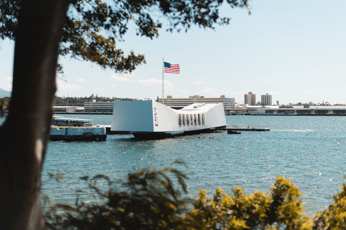 USS Arizona Memorial with a tour boat on the water, American flag flying