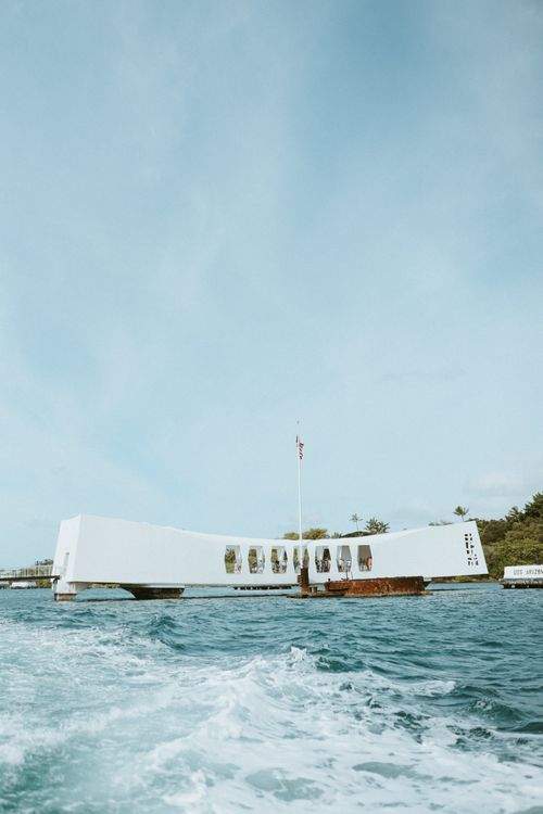 Classic view of the USS Arizona Memorial from the water, boat wake in the foreground