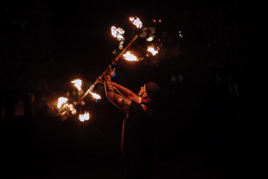 Fire dancer performing with flaming batons at night